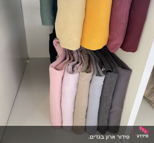 בגדים מקופלים ומסודרים בארון בצבעים שונים